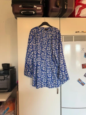 Blommig blå blus från Zizzi - Snygg blus från Zizzi med blått och vitt blommigt mönster. Blus har v-ringning och långa ärmar, vilket ger en chill och trendig vibe. Perfekt för dig som gillar färg och mönster! Materialet känns lätt och luftigt. Storlek XXL. Mycket fint skick, jag hittar inga synliga anmärkningar eller defekter. 