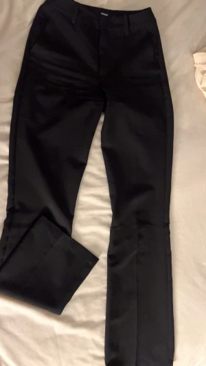 Svarta Kostymbyxor - Säljer dessa snygga, stilrena kostymbyxor som är i bra skick. Använda bara några gånger och fortfarande fräscha utan fläckar eller slitage. Perfekta både till vardag och fest. Storlek: 34, färg: svart. Passa på innan de försvinner!