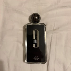 Afnan 9PM Eau de Parfum 100ml - Stilren parfym från Afnan med modern design. Det är ca 95ml kvar. Perfekt för dig som vill sticka ut med en unik och trendig doftaccessoar. Den efterliknar jean paul gaultier ultra male väldigt mycket. Lådan till parfymen är borta så bara parfymen.