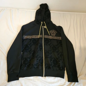 Svart hoodie med dragkedja - Svart hoodie med kedja och mönster,väldigt skön. OBS, INTE ÄKTA MÄRKE!