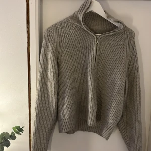 Grå stickad tröja med half zip - Säljer en grå stickad tröja med ribbad struktur och half zip-dragkedja i halsen. Tröjan har lång ärm och en lite högre krage som går att vika ner om man vill. Storlek M, men jag brukar ha S o den passar superfint.