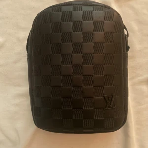 LW axelväska - En axelväska ifrån LW, använt den ett fåtal gånger inga defekter eller annat skick är 10/10. Axelväska har band som man kan justera längden på och väskan är svart med lite gråsvarta rutor. En fin väska för vardaglig användning mycket stilren och har en fin fashion stil till sig. 