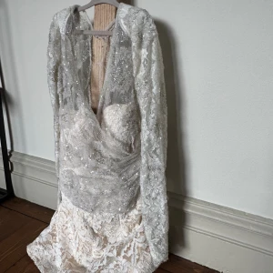 Byxdress med paljetter och spetts  - Byxdress i ljus spets med glittriga paljetter och broderade detaljer. BH-kupor och Långärmade ärmar, v-ringning och transparent mesh överdel. Ljusrosa spets shorts. Kan användas som topp eller byxdress. Storlek XS. 