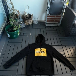 HUGO BOSS HOODIE  - Säljer en äkta Hugo Boss hoodie i svart med gulddetaljer – en riktigt lyxig och stilren hoodie som sticker ut. Hoodien är i väldigt fint skick, sparsamt använd och ser nästan ny ut. Perfekt för dig som vill ha märkesstil med premiumkänsla.  🖤 Färg: Svart med guld 📏 Storlek: Medium 💰 Nypris: ca 1800 kr 💸 Säljes för: 400 kr  Riktigt skön passform, mjukt material och snygga detaljer. Passar både till vardags och streetwear. Äkta Hugo Boss – först till kvarn!