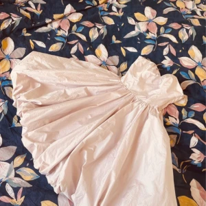 Ljusrosa puffig kortklänning - Superfin ljusrosa kortklänning med puffig kjol och axelbandslös överdel. Klänningen har en söt hjärtformad urringning och knappar längs ryggen. 