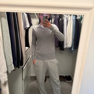 Filipa k - Snygg grå pikétröja med klassisk krage och knappar framtill. Tröjan har lång ärm och ribbade muddar vid ärmslut och nederkant. Passformen är slim och materialet känns mjukt och skönt mot huden. Perfekt för dig som gillar stilrena och enkla plagg.