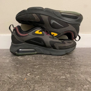 Nike Air Max 200 sneakers svart/gul - Nike Air Max 200 sneakers med svart mesh och syntet, detaljer i mörkrött, turkos och gul. Snygg vågig design på ovandelen, synlig Air Max-dämpning i sulan och klassisk snörning. Perfekt för dig som gillar streetstyle och sportig vibe. De är extremt sköna så det skulle vara perfekt för dig som inte vill känna sig obekväm men ändå ha stil.