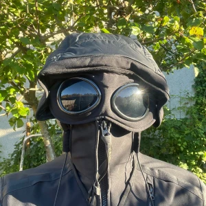 Cp company goggle jacka (autentisk) - CP company jacka med glasögonen som går att ha framför ögonen eller flippa up och ha på luvan. Shelljacka så perfekt för vinter och höst med massor av fickor, CERTILOGO finns på bild 3, skador inkluderar cigg hål och smått på glasögonen