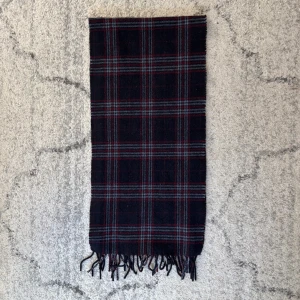 Svart halsduk i ull - Säljer denna snygga halsduk med klassiskt rutigt mönster i svart, rött och grått. Mycket bra skick och inga defekter, passar perfekt nu mot vintern. Tveka inte vid frågor eller prisförslag🧣🎓.