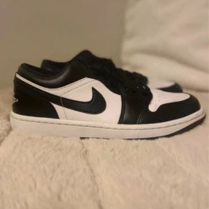 Nike Air Jordan 1 Low svart/vit EUR 40 - Säljer ett par Nike Air Jordan 1 Low i svart och vitt skinn. Klassisk siluett med svart snörning, perforerad tå och broderad Air Jordan-logga på hälen. Snygga kontraster och platt vit sula.