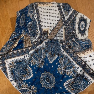 Boho mönstrad tubtopp - Vacker boho-inspirerad tubtopp i blått, vitt och brunt 💙 Smockad upptill och lätt utsvängd modell som sitter bekvämt. Perfekt till sommaren, festival, stranden eller under en kavaj för en chic look 🌞 I fint skick!