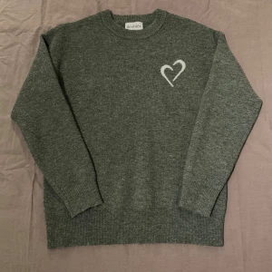 Grå stickad tröja Från Doublés - Mysig grå stickad tröja från doublés med en vit hjärtdetalj på bröstet. Tröjan har rund halsringning, ribbade muddar och lång ärm. Riktigt snygg och bekväm tröja med galet bra passform. Storlek S. Tröjan är använd cirka 2 gånger mycket varsamt. Hör av dig om du har några frågor!