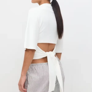 Vit croppad topp med knyt i ryggen - Säljer en vit croppad topp med halvlånga ärmar och snygg knytning i ryggen. Aldrig använd🥰