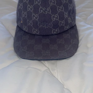 Gucci keps med GG-mönster marinblå - Snygg marinblå keps från Gucci med klassiskt GG-mönster över hela kepsen. Justerbar rem baktill i blått och insida i ljus bomull. Perfekt accessoar för dig som vill sticka ut med en exklusiv look. kan bytas 