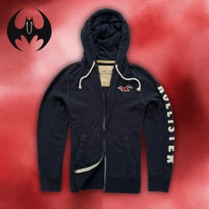 Mörkblå hollister hoodie med dragkedja - Mörkblå hoodie med dragkedja från Hollister med vit markerad text i vänster arm | size M/L | Längd: 70cm Armlängd: 68cm Axelbredd: 56cm | Passar mellan 170-185 cm 