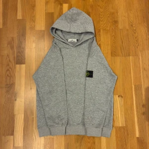 Grå hoodie från Stone Island M - Säljer en grå hoodie från Stone Island i storlek M. Klassisk modell med huva, magficka och den ikoniska Stone Island-patchen på armen.