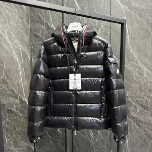 Svart pufferjacka från Moncler - Säljer en svart pufferjacka från Moncler med glansig finish och hög krage med logotypdetaljer. Jackan har dragkedja framtill, fickor på sidorna och en extra ficka på ärmen. Perfekt för kalla dagar och har en modern, sportig look. Använd ca 3 gånger passade inte mig. Passar L också