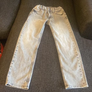 Ljusblå raka jeans med resårmidja - Snygga ljusgrå jeans med rak passform och resår i midjan för extra komfort. Klassisk femficksdesign och bälteshällor. Jeansen har en avslappnad vibe och är tillverkade i mjukt denimtyg som passar perfekt till sneakers eller boots. 146cm.