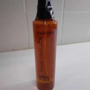 Matrix Mega Sleek Iron Smoother, Plattång spray,  shine, skydd.  - HELT NY OANVÄND Matrix Total Results Mega Sleek Iron Smoother är en orange sprayflaska med svart pump, 250 ml, köpt på Lyko. Produkten är en leave-in spray som hjälper till att skydda håret mot värme och friss, och ger ett slätt och glansigt resultat. Perfekt för dig som vill ha extra sleek hår. Har stått en tid men helt oanvänd och oöppnad med plombering kvar på.