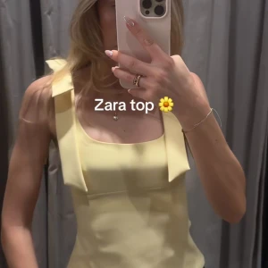 Gul linnetopp med knyt från Zara - Supersöt ljusgul linnetopp från Zara med breda axelband som knyts i rosetter. Toppen har en fyrkantig ringning och lätt figursydd passform. Perfekt för sommarens alla tillfällen och ger en fräsch vibe till din outfit.