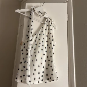 Prickig vit topp med knyt - Säljer en vit omlott topp med svarta prickar och snygg knytning vid halsen. Väldigt fin och populär ⭐️⭐️