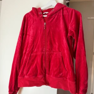 Röd velour hoodie med dragkedja - Mjuk och skön röd hoodie i velour med huva och dragkedja framtill. Står L men passar mer som en M!