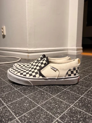 Vans Checkerboard Slip-On sneakers - Klassiska Vans Slip-On sneakers med svartvitt rutigt mönster. Är använd fåtals gånger, kan gå ner i pris vid snabb affär, 