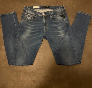 Replay Anbass blå jeans W31 L34 - Tvär snygga Replay Anbass jeans i klassisk blå tvätt med diskreta slitningar och kontrastsömmar. Sitter perfekt på, vid frågor och funderingar tveka inte av att höra av dig!!