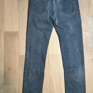 Grå jeans från Jacob Cohen - Snygga grå jeans från Jacob Cohen med klassisk femficksdesign och silverfärgade knappar. Jeansen har raka ben och normal passform, tillverkade i mjukt bomullsmaterial. Perfekt för dig som gillar stilrena och tidlösa jeans.