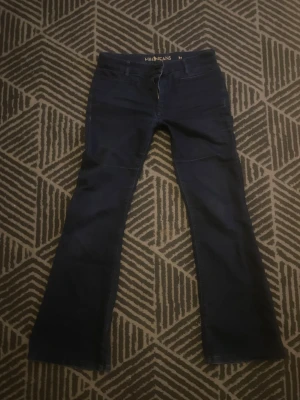 LOWWAIST bootcut jeans från MiH Jeans - Snygga mörkblå jeans från MiH Jeans med klassisk bootcut passform. Jeansen har fem fickor, guldiga nitar och en liten broderad fågel på bakfickan. Materialet är mjukt denim och midjan är normal. Perfekt för dig som gillar retrovibbar och stilren look.