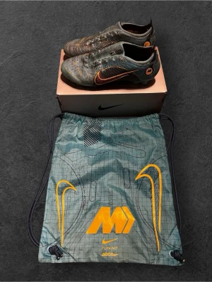 Nike Vapor 14 Elite FG fotbollsskor - Nike Vapor 14 Elite FG fotbollsskor i färgen chlorine blue och laser orange. Skorna har en snygg, sportig design med orange detaljer och Nike-logga på sidan. Tillverkade i lätt syntetmaterial med snörning och platt sula för bästa grepp på planen. Kommer med originalpåse.