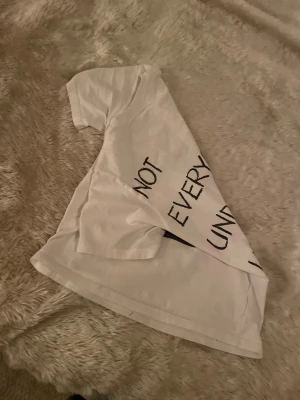 Vit t-shirt med house music-tryck - Vit t-shirt i bomull med svart tryck på ryggen: 'Not everyone understands house music' och en cool DJ-mixer grafik på framsidan. Klassisk rund hals och korta ärmar, perfekt för dig som älskar elektronisk musik och vill sticka ut. Storlek xs men den passar 12-15 år