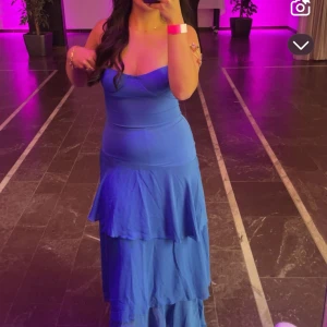 Blå långklänning med volanger - Säljer min snygg balklänning som är blå och lång, med smala axelband. Jag har endast använd den en gång. Original priset tillsammans med frakt ligger vid ca 1700kr, då jag har beställt den från USA.