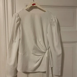 Vit blus med knytdetalj i midjan - Snygg vit blus med långa ärmar och puff vid axlarna. Blusen har en knutdetalj vid midjan som ger en mer ”snatched ” look 👀 