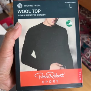 Svart merinoullströja  Pierre Robert L - Svart långärmad tröja från Pierre Robert i sportig stil, tillverkad av 70% merinoull och 30% Tencel. Modellen är enkel och tight med rund hals. Perfekt för lager-på-lager och outdoor-aktiviteter.