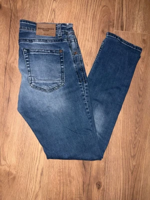 Blå skinny jeans från Dsquared2 - Snygga blå jeans från Dsquared2 med klassisk femficksdesign och diskreta slitningar framtill. Jeansen har en skinny passform och låg midja, vilket ger en modern och tajt look. Materialet är stretchigt denim som sitter bekvämt hela dagen.