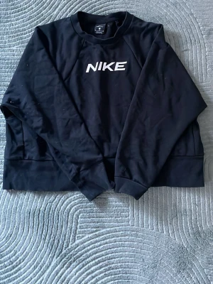 Svart Nike sweatshirt Dri-FIT - Svart sweatshirt från Nike med vit logga på bröstet och rund hals. 
