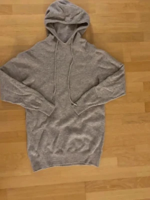 Beige tröja med snören  - Mysig beige hoodie med huva och långa ärmar. Utrustad med dragsko i huvan och ribbade muddar vid ärmslut och nederkant. Perfekt för en avslappnad stil. xs-s