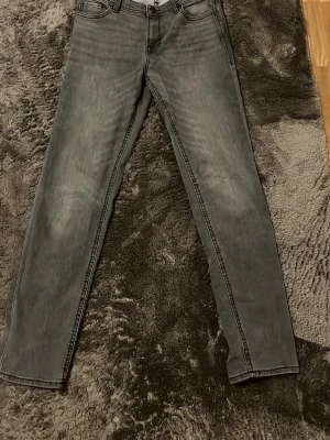 Gråa Jack&Jones jeans - Snygga grå jeans med raka ben och klassisk femficksmodell. Jeansen har en diskret tvättad look och är tillverkade i mjukt bomullsjeansmaterial. Perfekta för dig som gillar en enkel och stilren vibe. Sitter som W29 L30, var itne rädd för att ställa frågor. Pris går att diskuteras