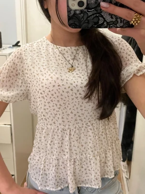 Vit blommig volangblus - Supersöt vit blus med små blommor i beige och brunt. 