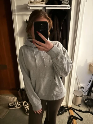 Grå basic hoodie med huva - Enkel och stilren grå hoodie med huva och dragsko. Mjuk insida och stor magficka framtill. Perfekt för en avslappnad look och passar till det mesta. Klassisk modell utan synligt märke.