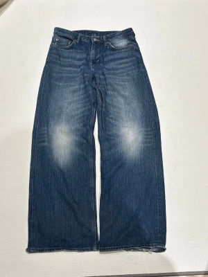 Baggy jeans, Weekday Ample, W27 L32 - Snygga blåa baggy jeans💙 Från Weekday, modell ample💙 Storlek W27, L32💙 Använda men i fint skick, inga skavanker utöver slitningar i hälarna (bild 5)💙 Säljs då de ej passar längre💙  Mått:  Midja - 39cm  Hel längden - 102cm  Innerben - 77cm  Benöppning - 27cm   Skriv om du har frågor eller prisförslag🥰