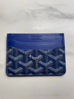 Korthållare i läder - Snygg korthållare i blått med klassiskt chevron-mönster. Slimmad modell som är smidig att ha i fickan eller liten väska. Flera kortfack på båda sidor samt ett extra fack i mitten. Använd men i fint skick