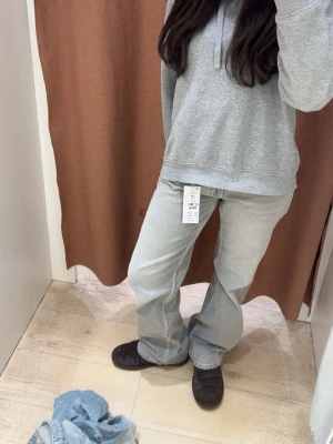 Gråa vida jeans från Gina Tricot - Säljer ett par ljusgrå jeans från Gina Tricot med rak och något vidare passform. Jeansen har klassiska fem fickor, knappgylf och coola fickdetaljer bak. Passar både folk med xs och s