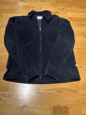 Marinblå manchester overshirt - Snygg marinblå overshirt i manchester. Jackan har dragkedja framtill, klassisk krage och två bröstfickor. Perfekt lager-på-lager-plagg med avslappnad passform och stilren look.