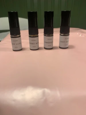 Fyra parfymprover i miniflaskor från Curiosa - Säljer fyra små parfymprover i genomskinliga glasflaskor med svarta plastlock. Doftnamnen är Lady Luxe, Cherry Musk, Limonette och Lost in Lust. Flaskorna har enkel, stilren design med vita etiketter och svart text. Perfekt för dig som vill testa olika dofter.
