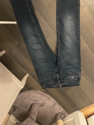 Mörkblå jeans från Tommy Hilfiger - Snygga mörkblå jeans från Tommy Hilfiger med klassisk femficksdesign och diskret logga på bakfickan. Jeansen har normal passform och är tillverkade i mjukt denimtyg med lätt tvättade detaljer. Perfekta för en stilren look. Nya!