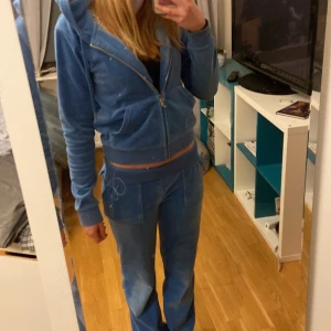 Blått Juicy Couture sett - Säljer ett snyggt och mjukt juicy sett i färgen blå! Byxorna är i storlek XS och tröjan är i storlek S. Bra kvalité men lite smutsiga längst ner vid hälarna men absolut inget man tänker på. Snöret saknas på byxorna 