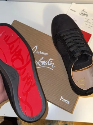 Christian Louboutin Svarta Skor - 👟 Christian Louboutin Sneakers ✔️ 100 % original ✔️ Färg: Svart ✔️ Material: Mocka ✔️ Ikonisk röd sula ✔️ Skick: Mycket bra (se bilder) ✔️ Inkluderar originalkartong & dustbag  📦 Snabb frakt 💬 Hör av dig vid frågor 🔁 Öppen för rimliga bud 