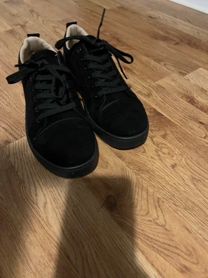 Röd sula skor ja vene vad de heter  - Stilrena svarta sneakers  med ovandel i mocka och klassisk snörning. Skorna har en platt sula och rund tå, samt ljus insida som kontrast. Perfekta för dig som gillar en clean och enkel look.